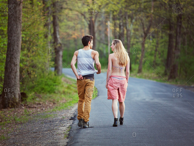 Rear view of couple walking on road in forest