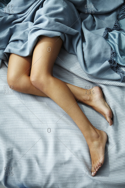 Legs of young Caucasian woman on bed in the morning