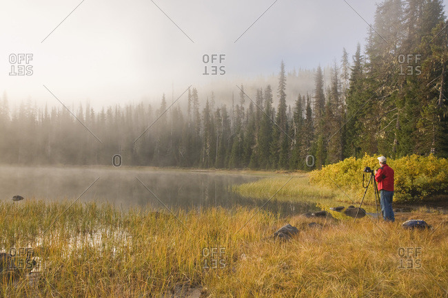 USA,  Oregon,  Willamette National Forest Male photographer at work next to Scott Lake on foggy morning