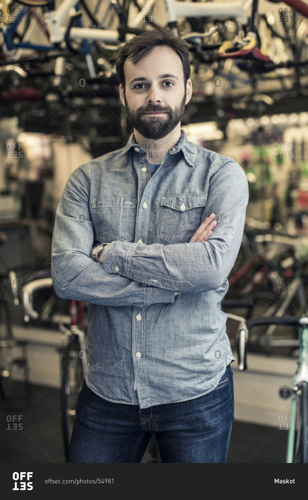Portrait of confident  male owner standing arms crossed at bicycle repair shop