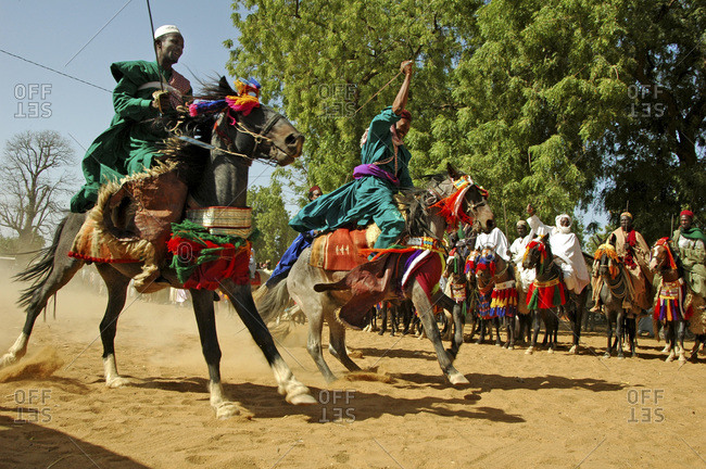 Cameroon, Pouss. African horsemen riding a horse racing on a dusty ...