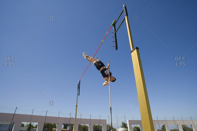 Male pole vault athlete going over bar, low angle view