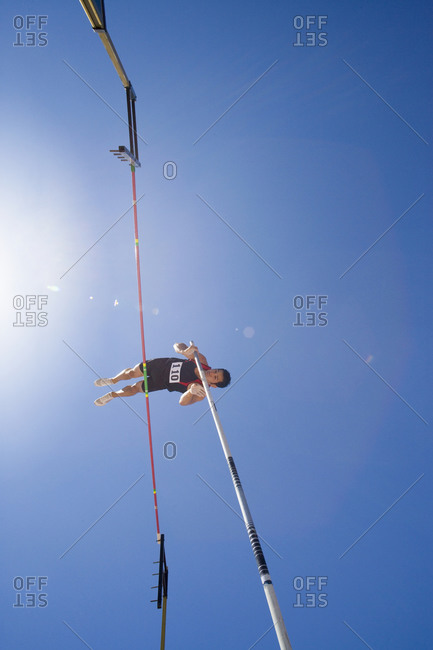 Pole vault athlete going over bar, low angle view