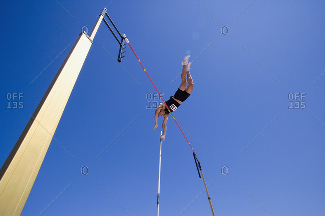Pole vault athlete going over bar, low angle view