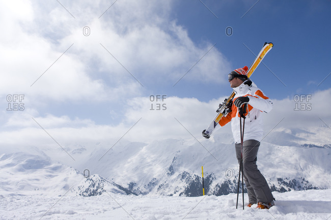 Skier on remote mountain top carrying skis