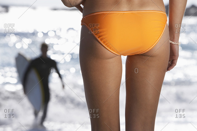Young woman in swimsuit walking on the beach during sunset stock photo -  OFFSET