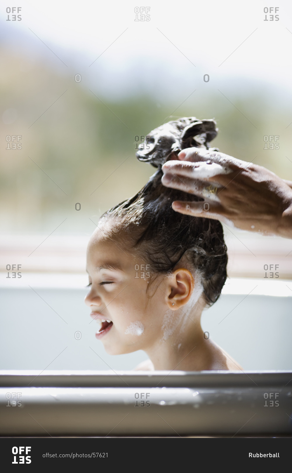 Girl in bathtub having hair washed