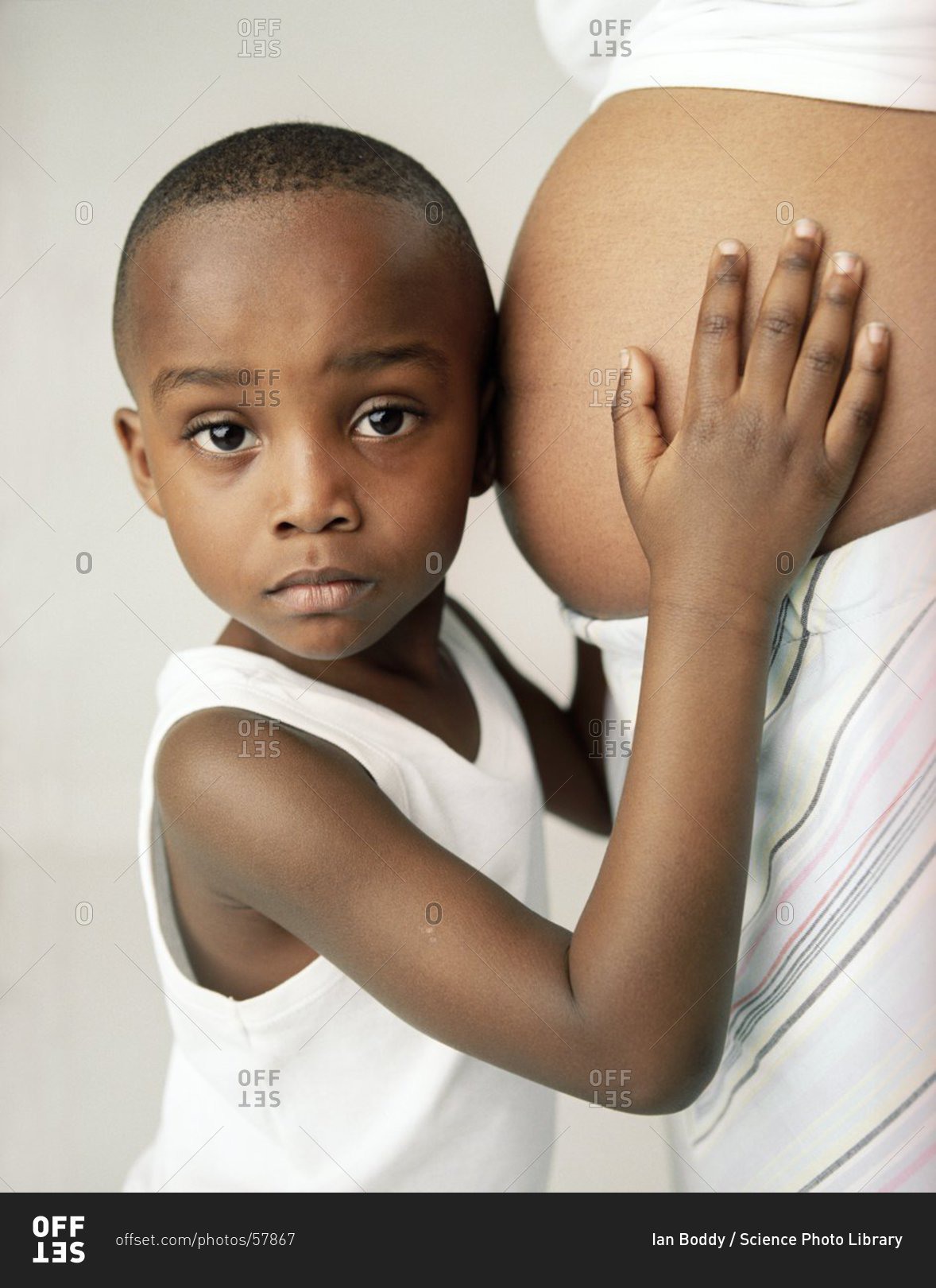 Pregnant woman and son. 4-year-old boy holding and listening to the swollen abdomen of his mother
