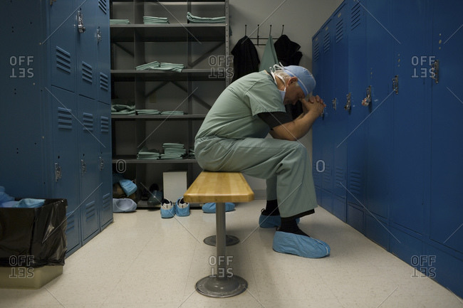 Surgeon sitting in locker room with head in hands
