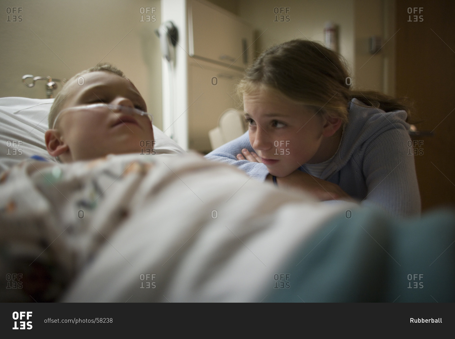 Young girl sitting by brother in hospital bed