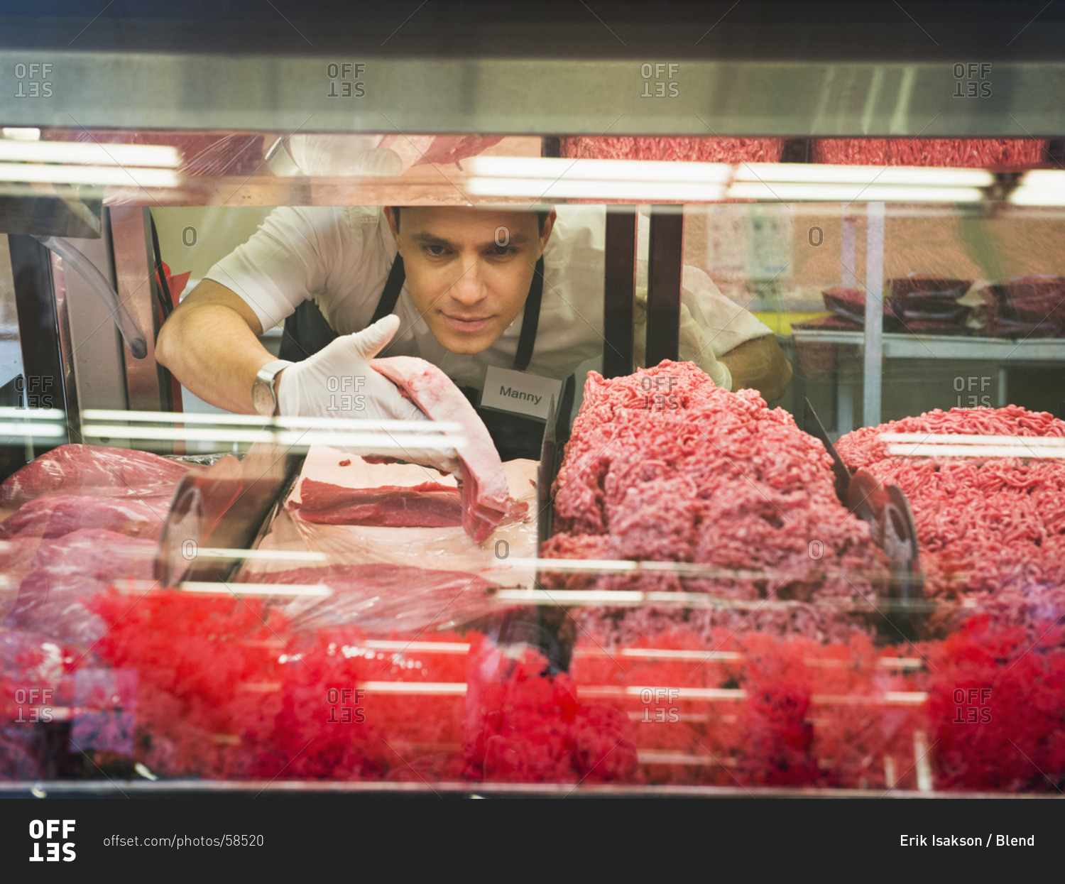 Hispanic butcher at meat counter of grocery store