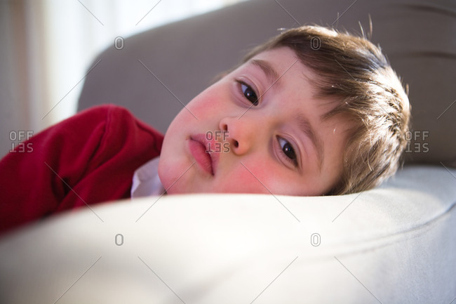 Little Boy Rests His Head On A Pillow With A Sad Look On His Face