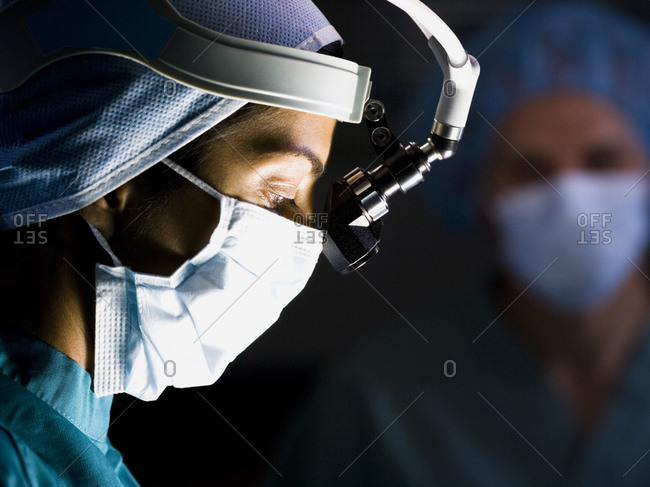 Male doctor in scrubs with head light in surgery