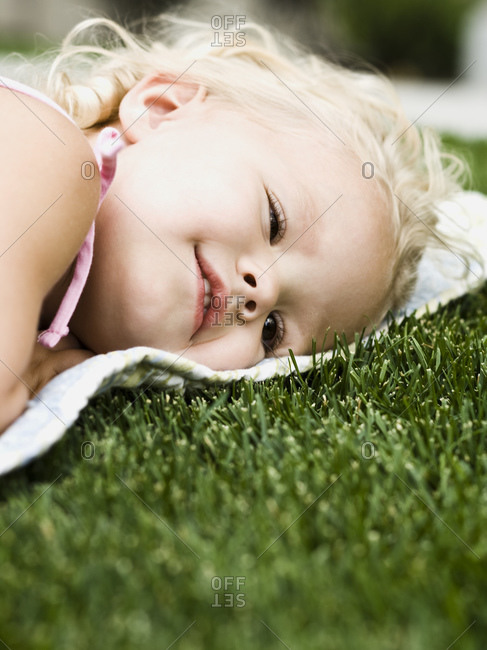 Little girl lying on a blanket on the grass.