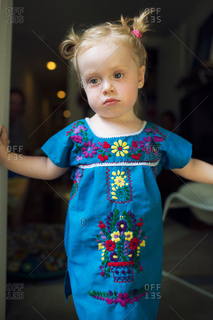 Little girl in embroidered dress standing in doorway