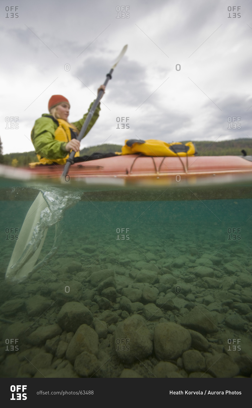 Woman sea kayaking on a lake as seen from below deep in Glacier National Park
