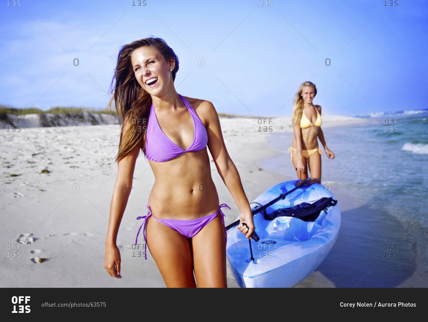 Two girls walk with a sea kayak along Pensacola Beach, Florida