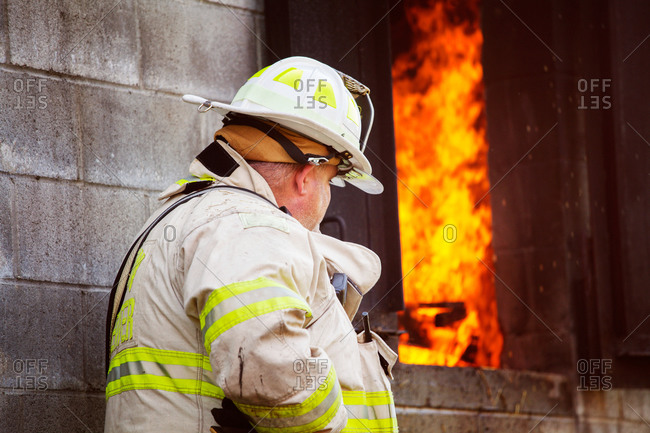 Fireman standing next to a burning building
