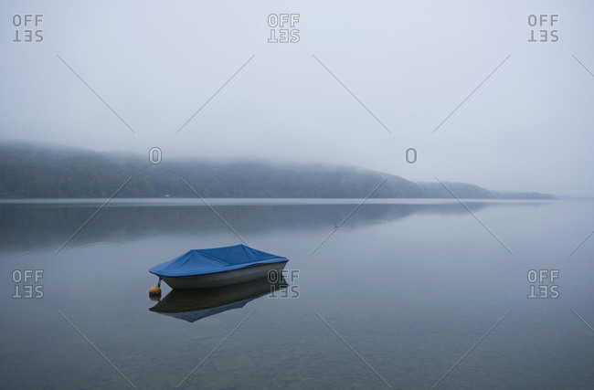 Boat anchored in the foggy Wallersee lake in Flachgau, Land Salzburg, Austria