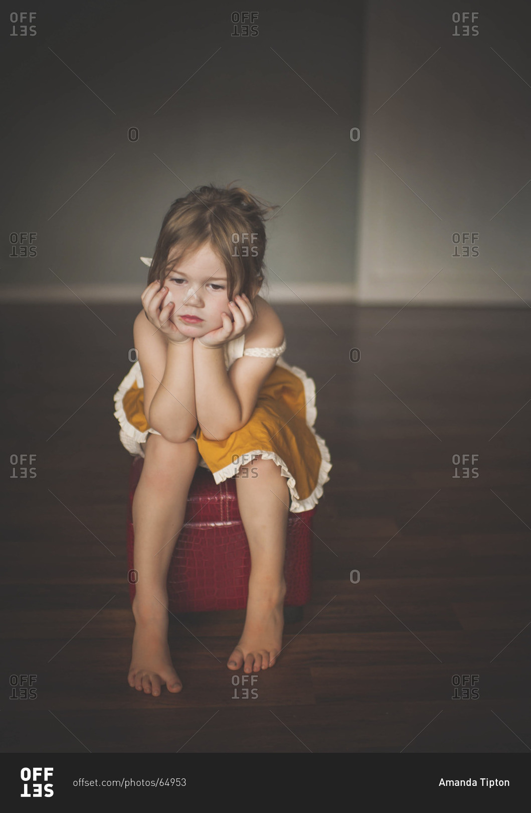 Young girl looking sad while sitting on stool