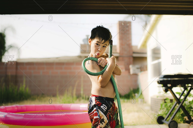 Young boy posing with hose in countryside