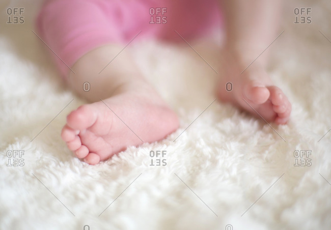 Low-section view of little baby lying on white furry blanket