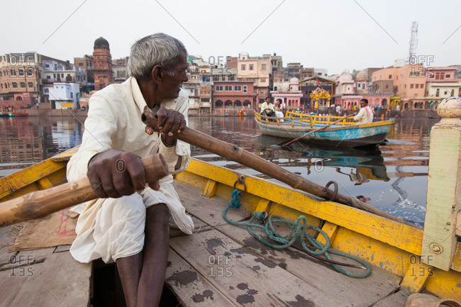 Elderly Indian man rowing boat in Varanasi, India