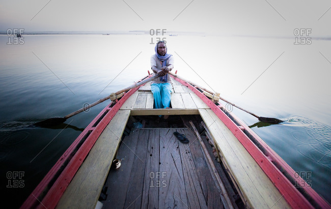 Indian man rowing boat in Varanasi, India