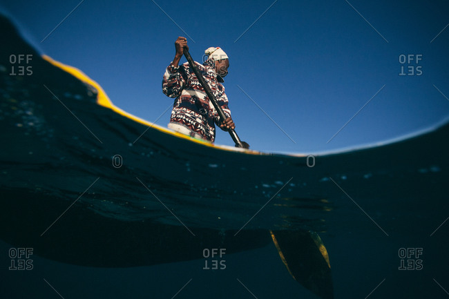 Young vezo fisherman with paddle seen above and below the water in Madagascar