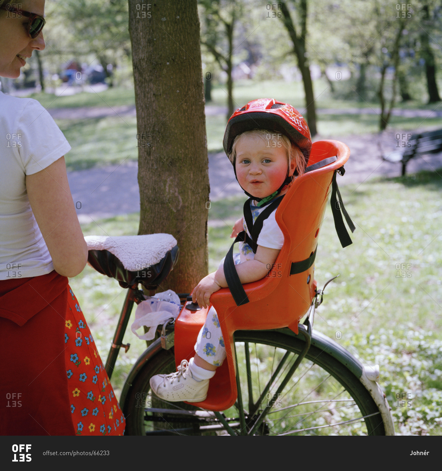 A little girl sitting in a child''s seat on a bicycle