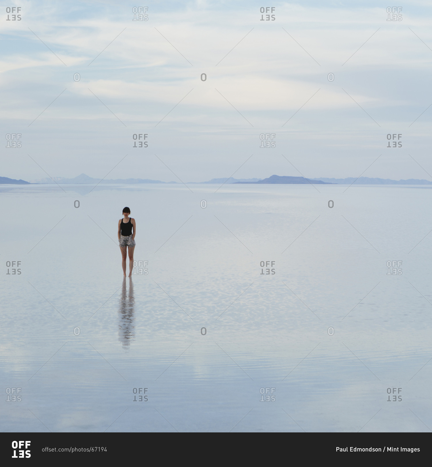 A woman standing on the flooded Bonneville Salt Flats, at dusk