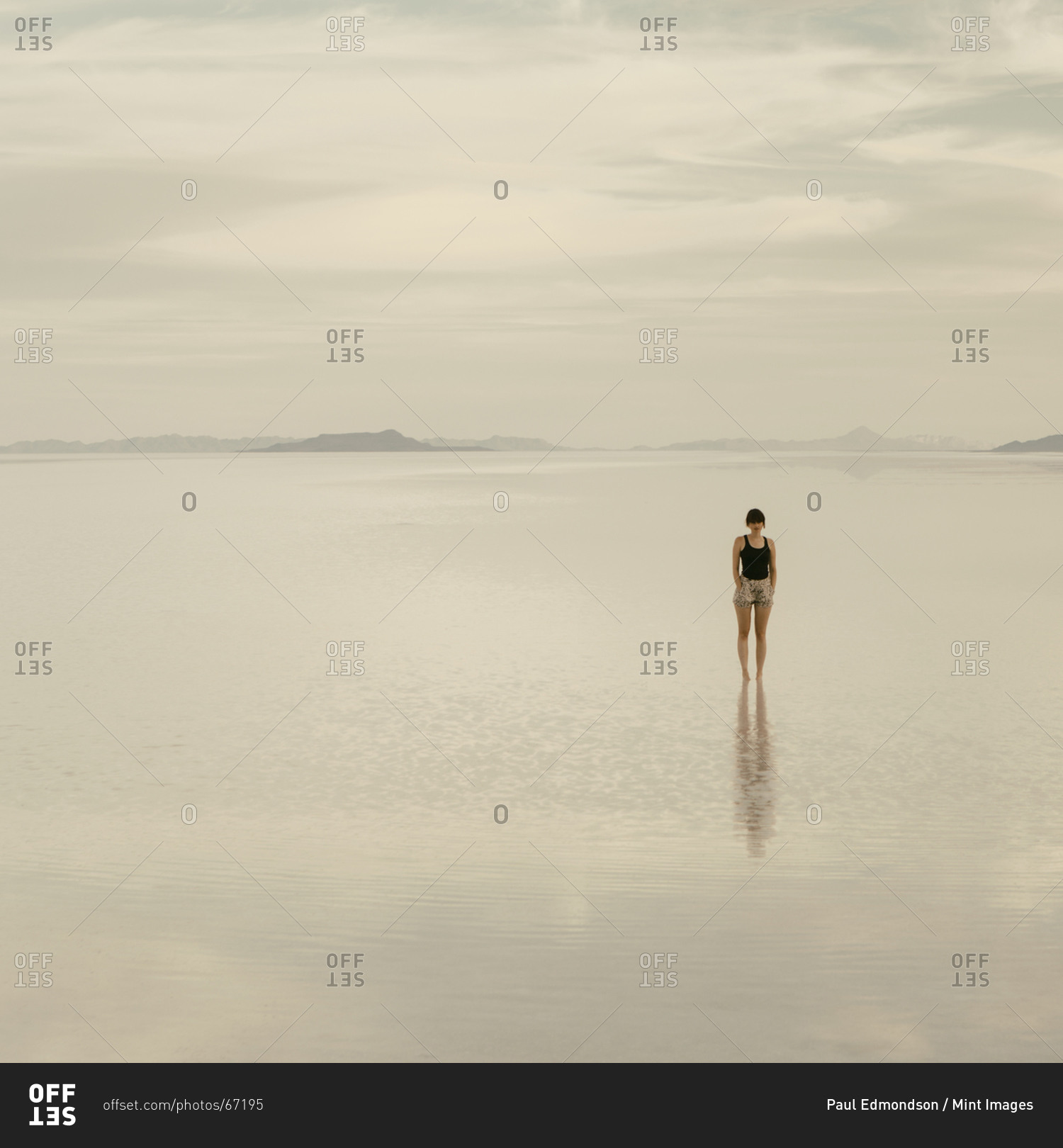 Woman standing on the flooded Bonneville Salt Flats, at dusk