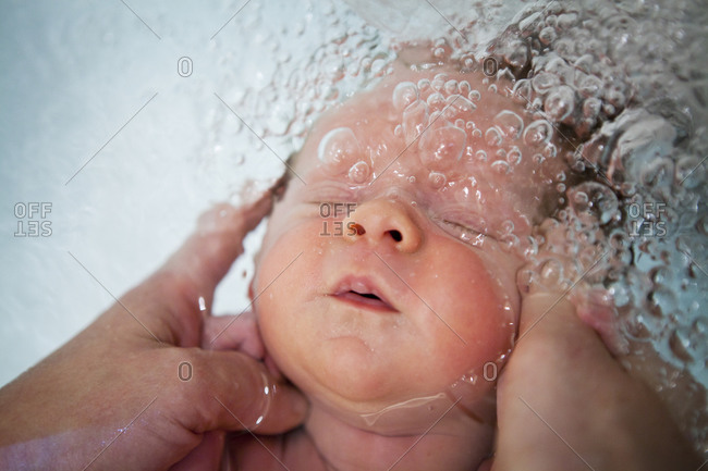 Pediatric nursing assistant bathing a  3 weeks old baby