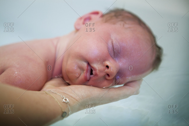 Pediatric nursing assistant bathing a  3 weeks old baby