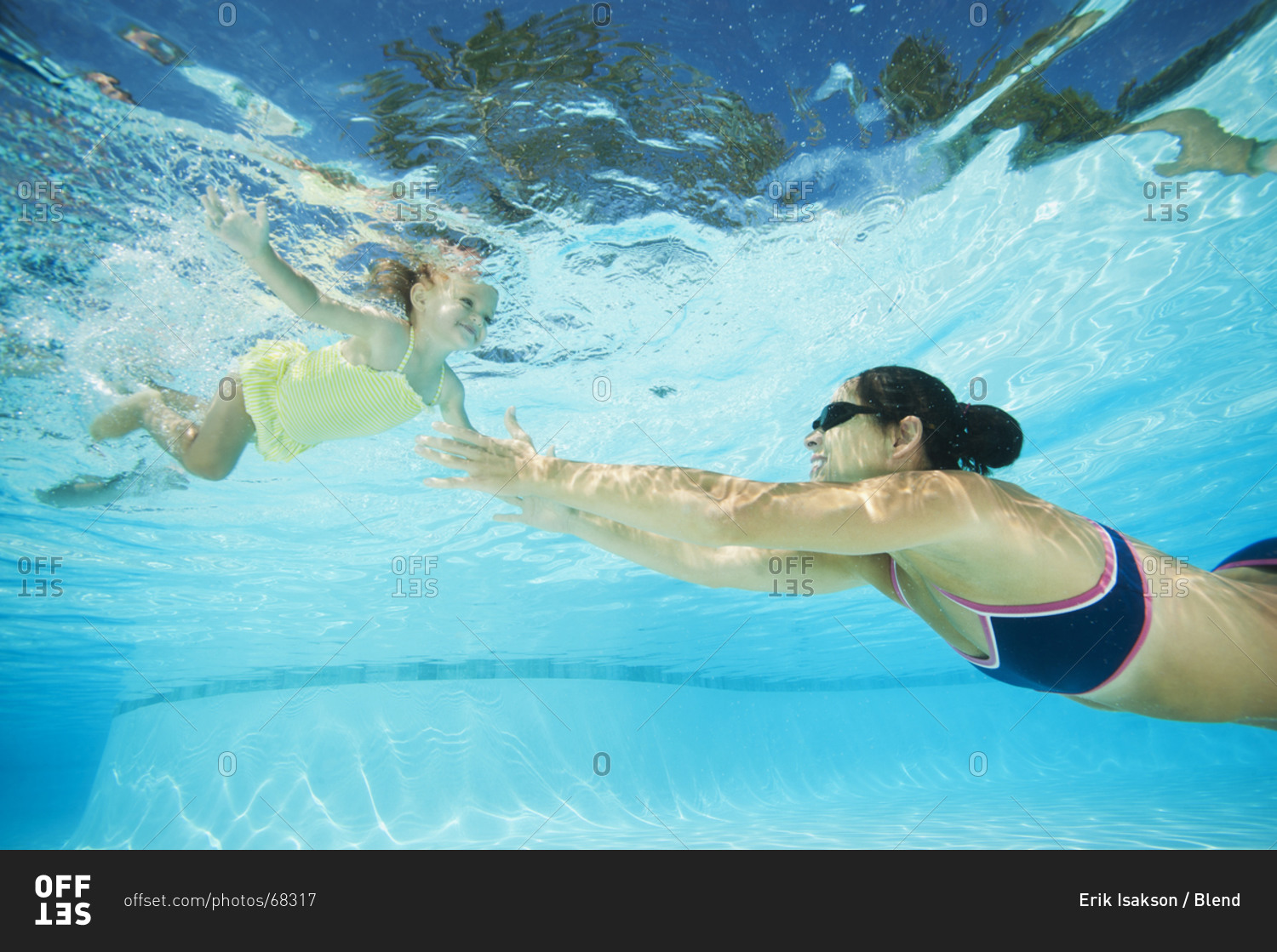 Mother swimming in swimming pool with daughter