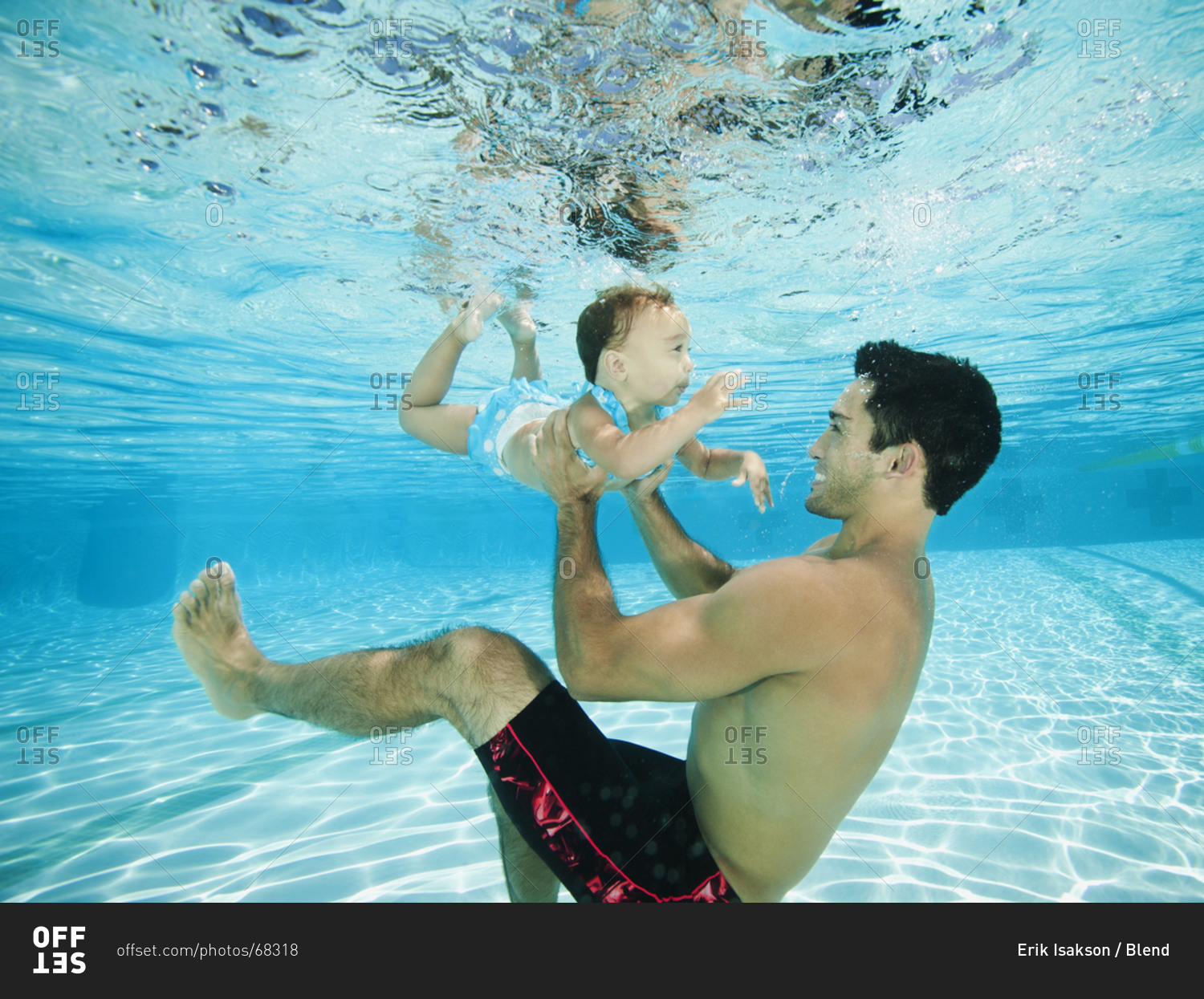 Father swimming underwater with daughter in swimming pool