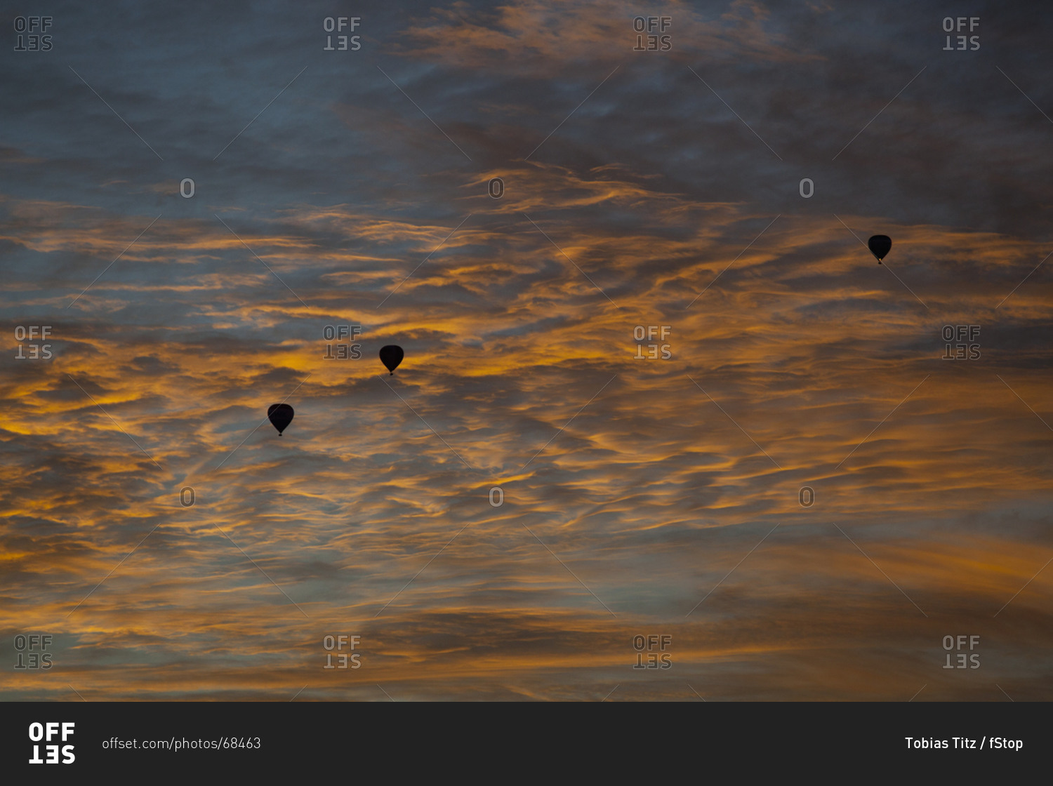 Three silhouetted hot air balloons against a dusk sky