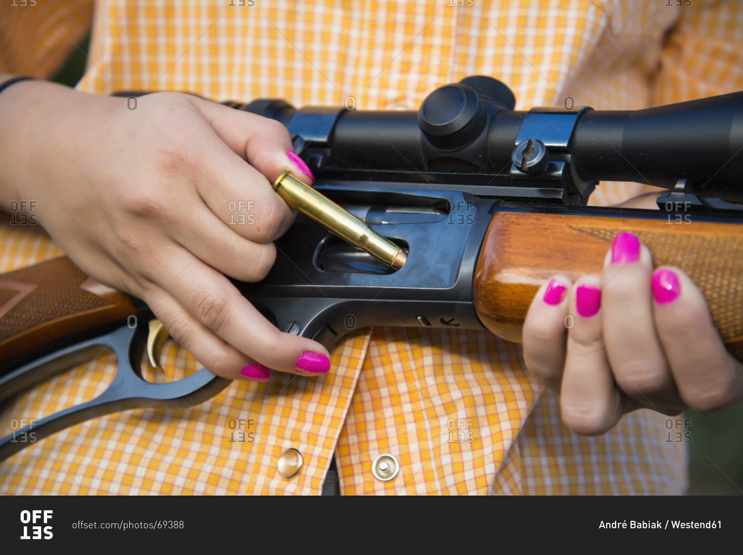 Young woman inserting bullet in hunting rifle