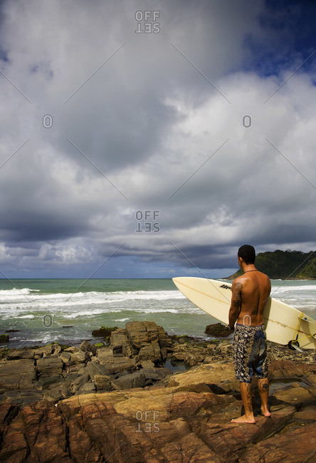 Rear view of young man with surfboard