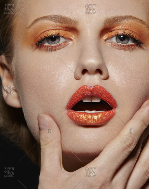 Model posing in orange eye shadow and lipstick