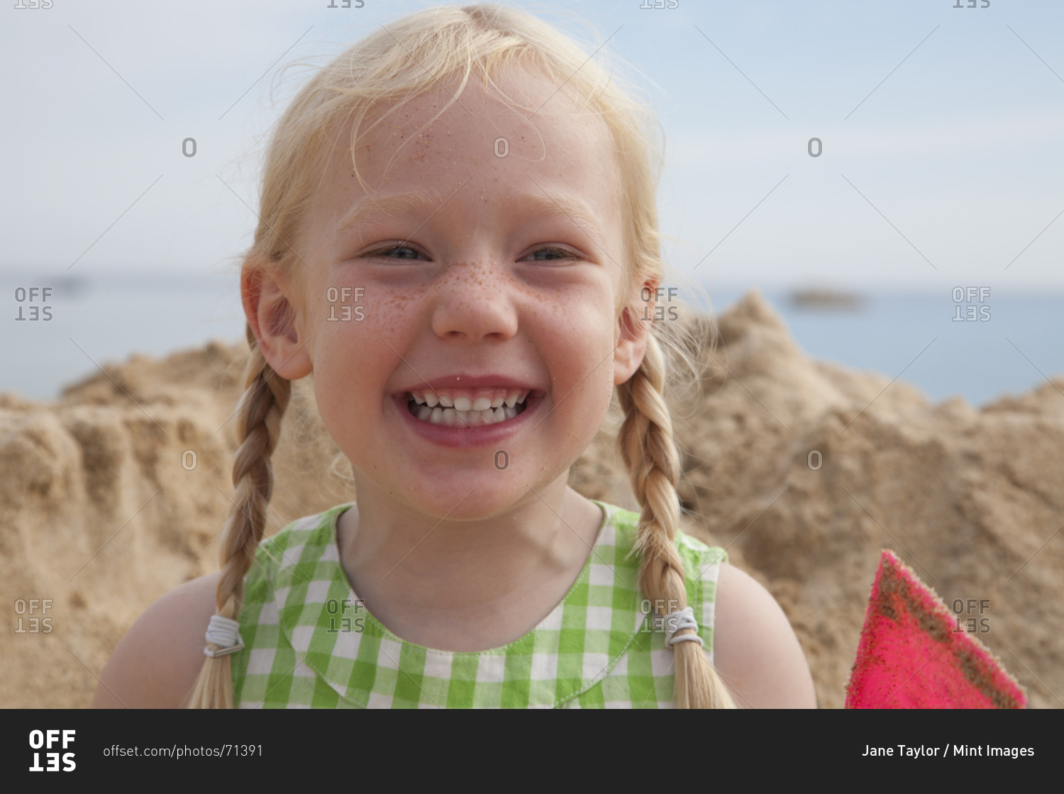 Young cheerful girl in front of huge pile of sand