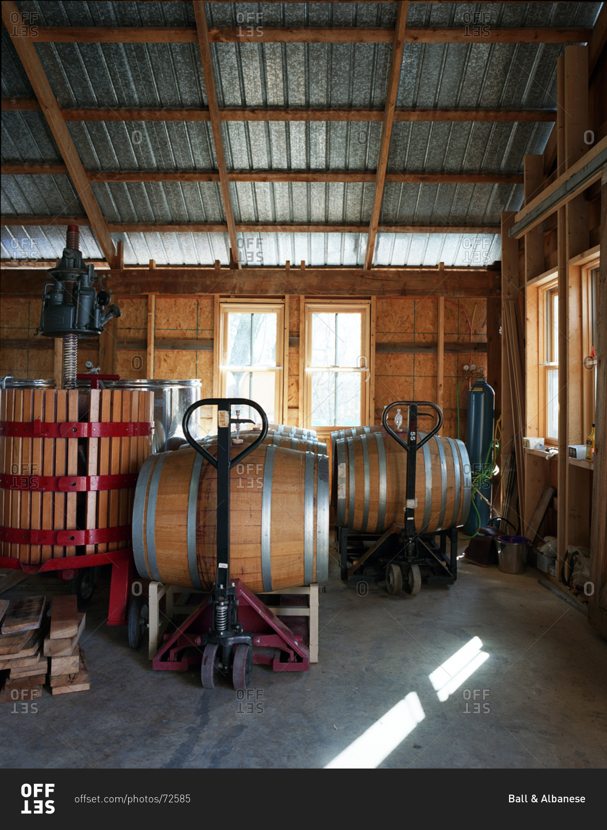 Wine press and oak barrels in warehouse