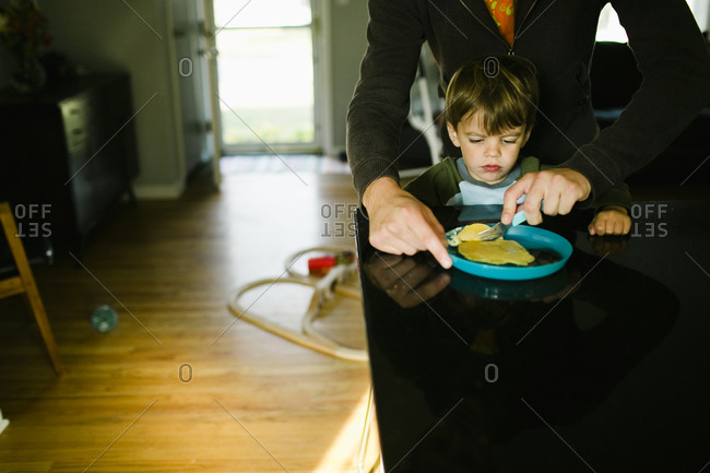 Young boy waits for his breakfast while been prepared by parent