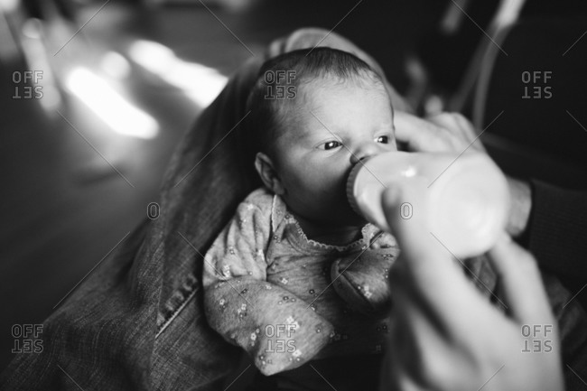 Parent feeding baby milk from a bottle