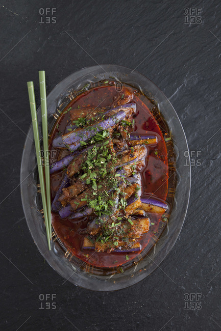 Served Asian red-cooked eggplant garnish with peppercorns, dill, chives, and chili oil