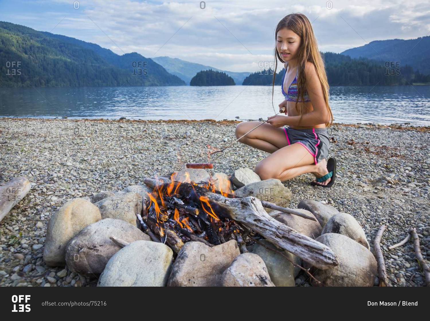 Young girl roasting a hot dog at campfire