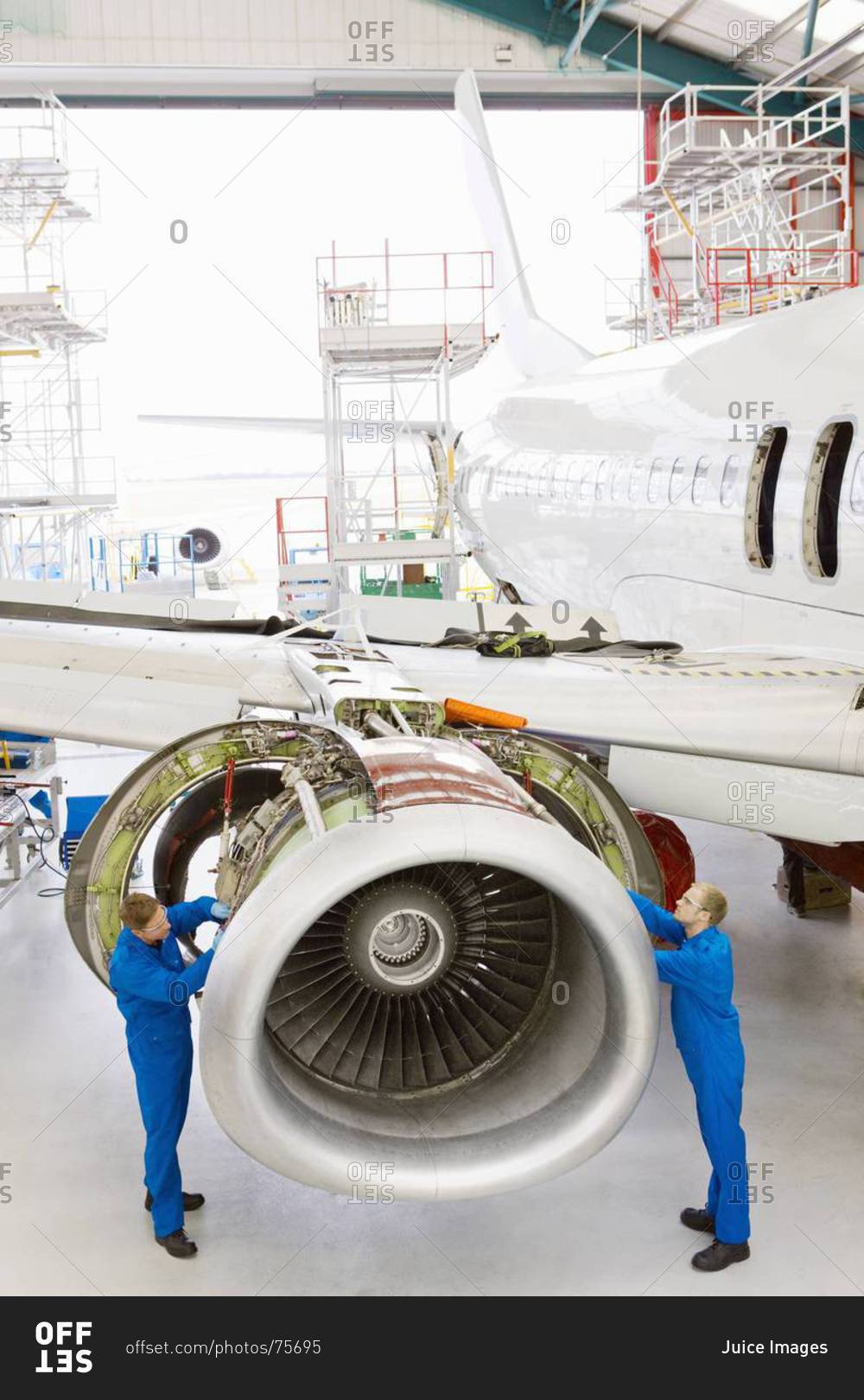 Engineers assembling engine on passenger jet in hangar