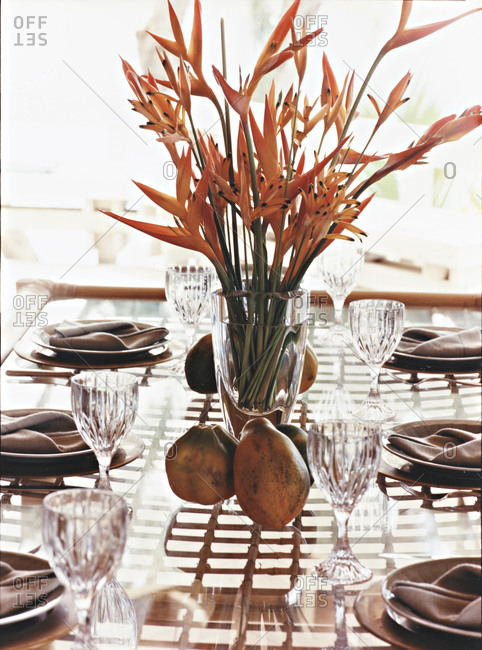 Still life of table setting with birds of paradise flowers and papayas as ornamentation