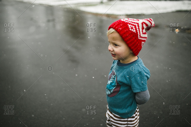 Toddler boy standing in snowing on wet road