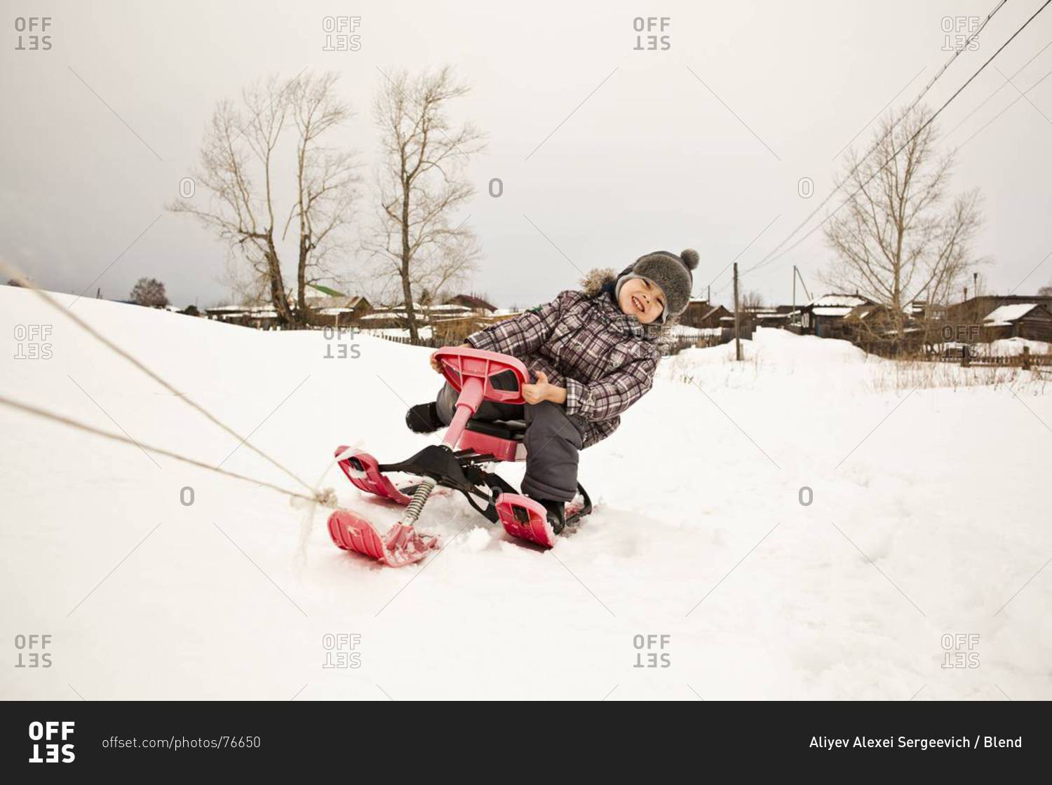 Asian girl riding sled in snow